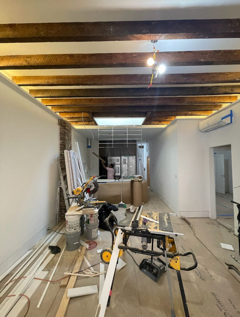 In-progress house remodel showing ceiling beam restoration, electrical updates, and custom tile installation.