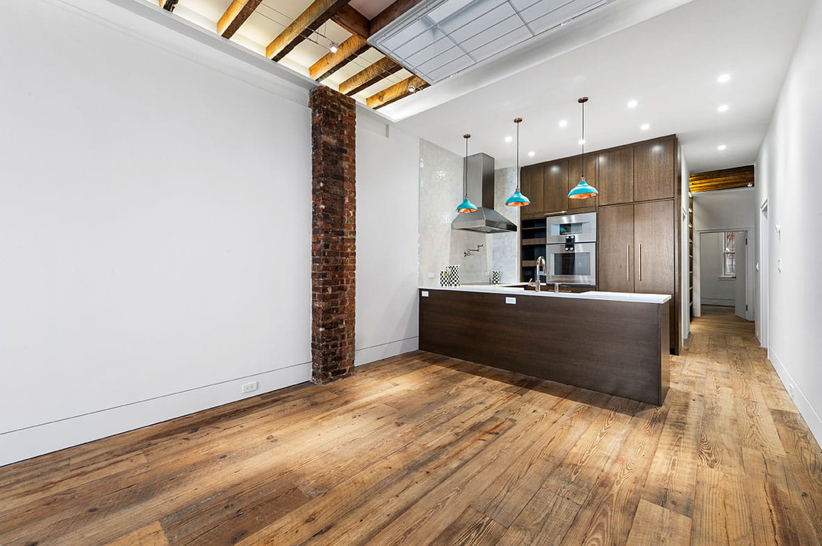 Complete house remodel in Brooklyn showing open kitchen design with industrial brick accents and restored wood beams.