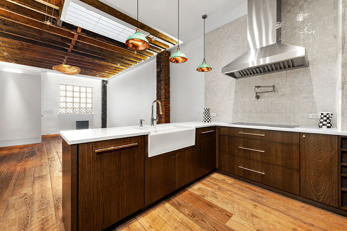 Complete house remodel in Brooklyn showing open kitchen design with industrial brick accents and restored wood beams.