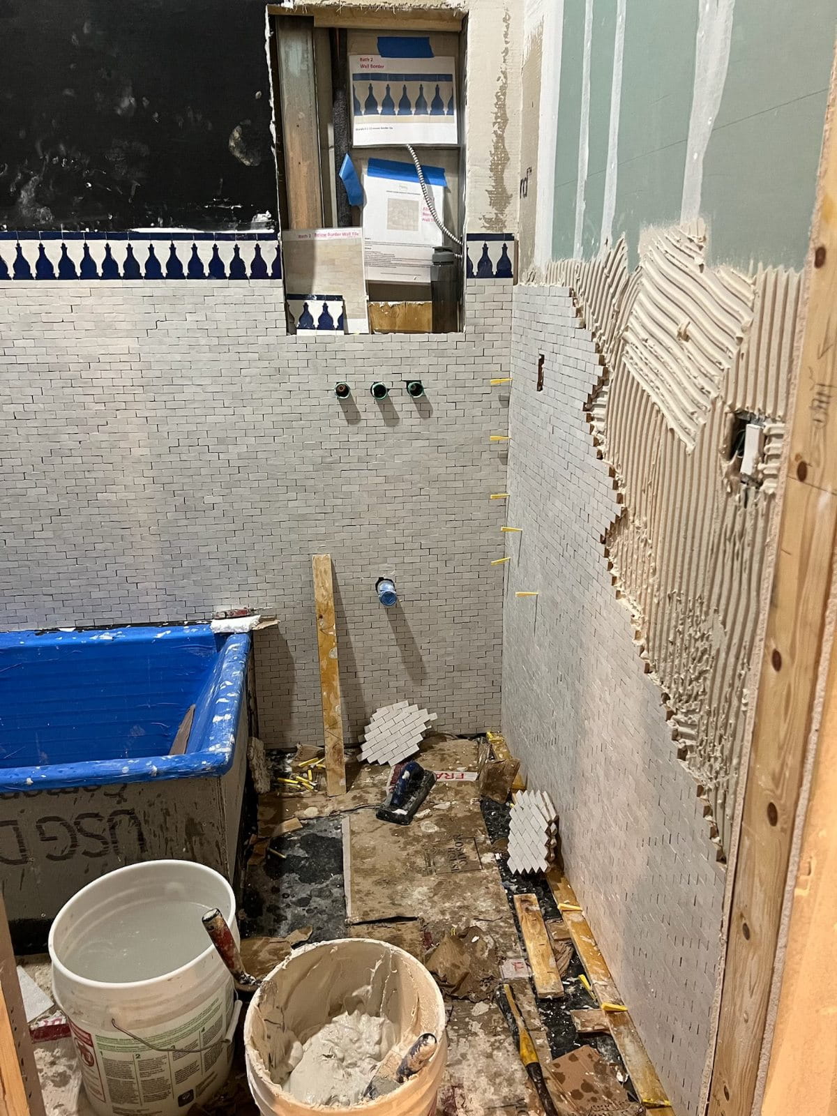 In-progress house remodel showing ceiling beam restoration, electrical updates, and custom tile installation.